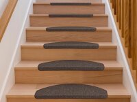 Eine gerade Holztreppe mit sechs Stufen, jede Stufe ist mit einem halbrunden, dunklen Teppichtritt belegt. Links und rechts sind weiße Wände und ein hölzernes Treppengeländer zu sehen.