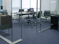 Modernes, leeres Besprechungszimmer mit Glastrennwänden, rundem Tisch, mehreren schwarzen Bürostühlen, einem Laptop, Schreibutensilien und hellen Fenstern im Hintergrund.